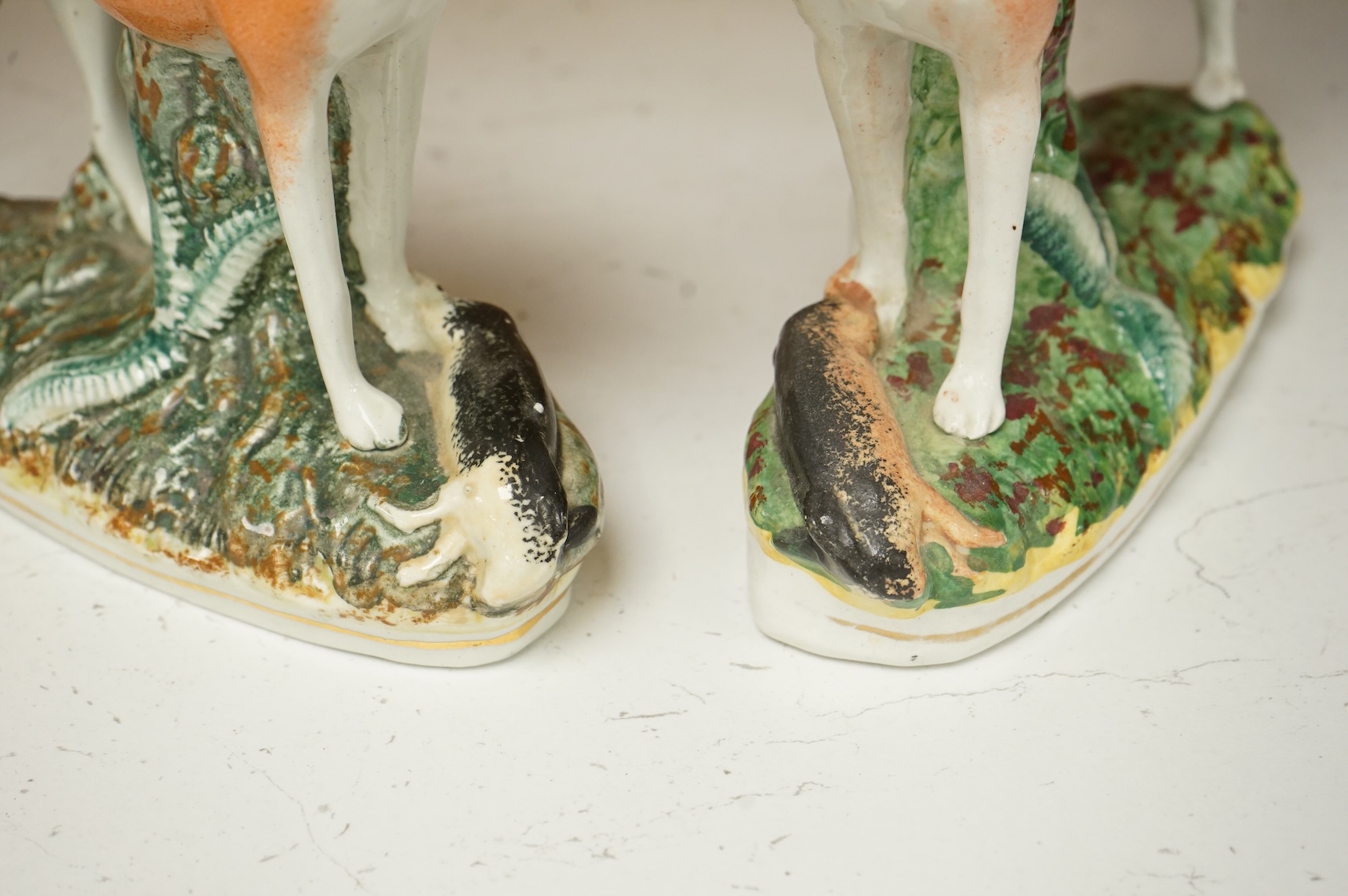 A pair of Staffordshire whippets, 19th century, one damaged, 19cm wide